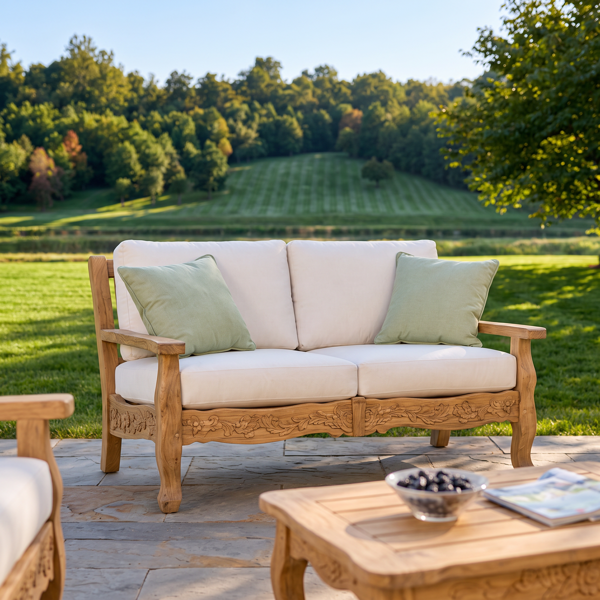Kingsley Bate Normandy teak settee with throw pillows on a stone patio