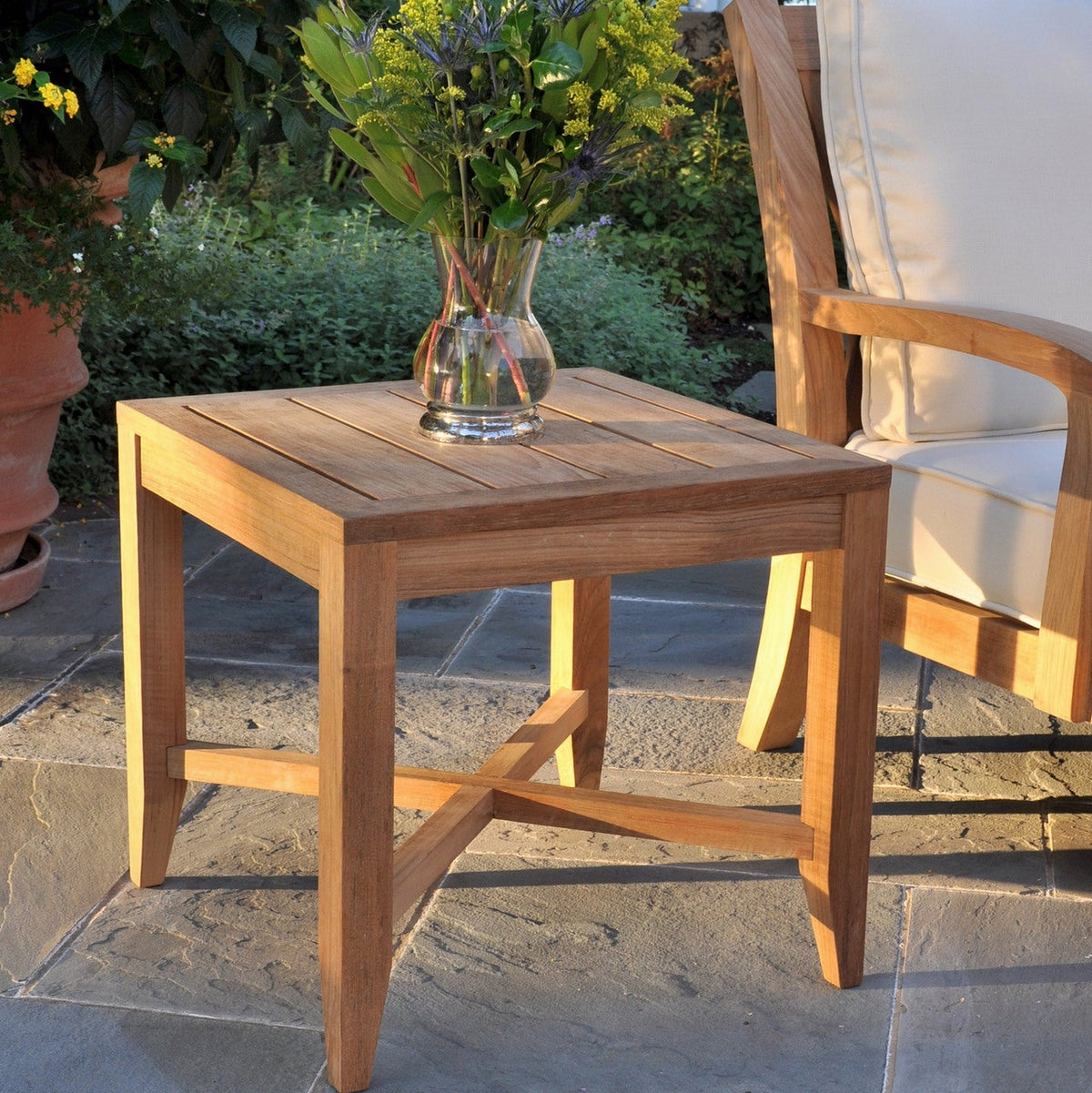 Kingsley Bate Somerset teak side table beside a lounge chair on a patio