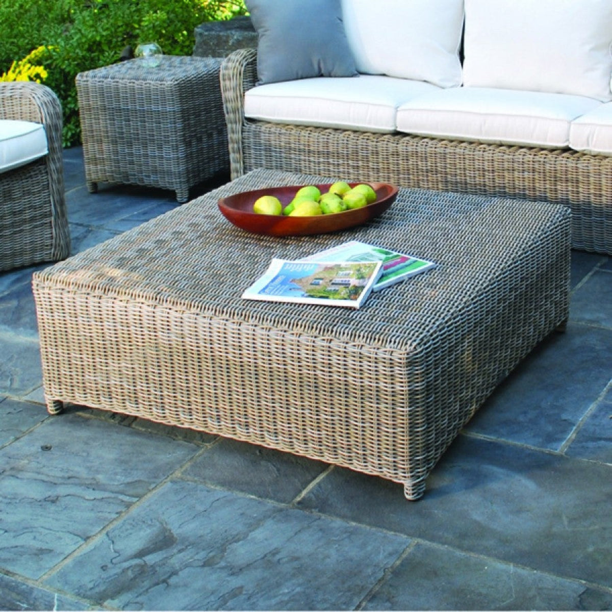 Kingsley Bate Sag Harbor wicker chat table with sofa on a stone patio