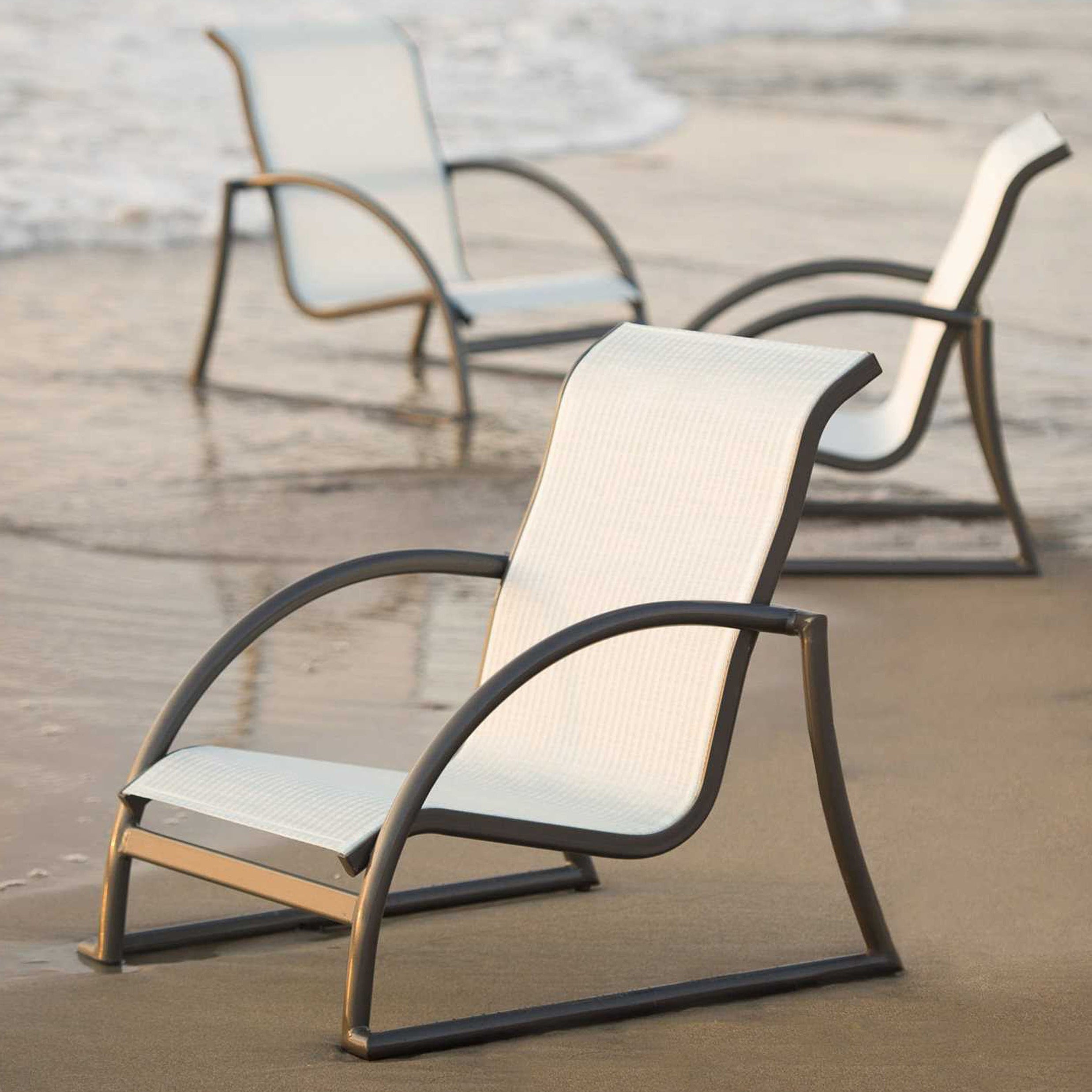 Beach chairs on a sandy beach with ocean waves in the background