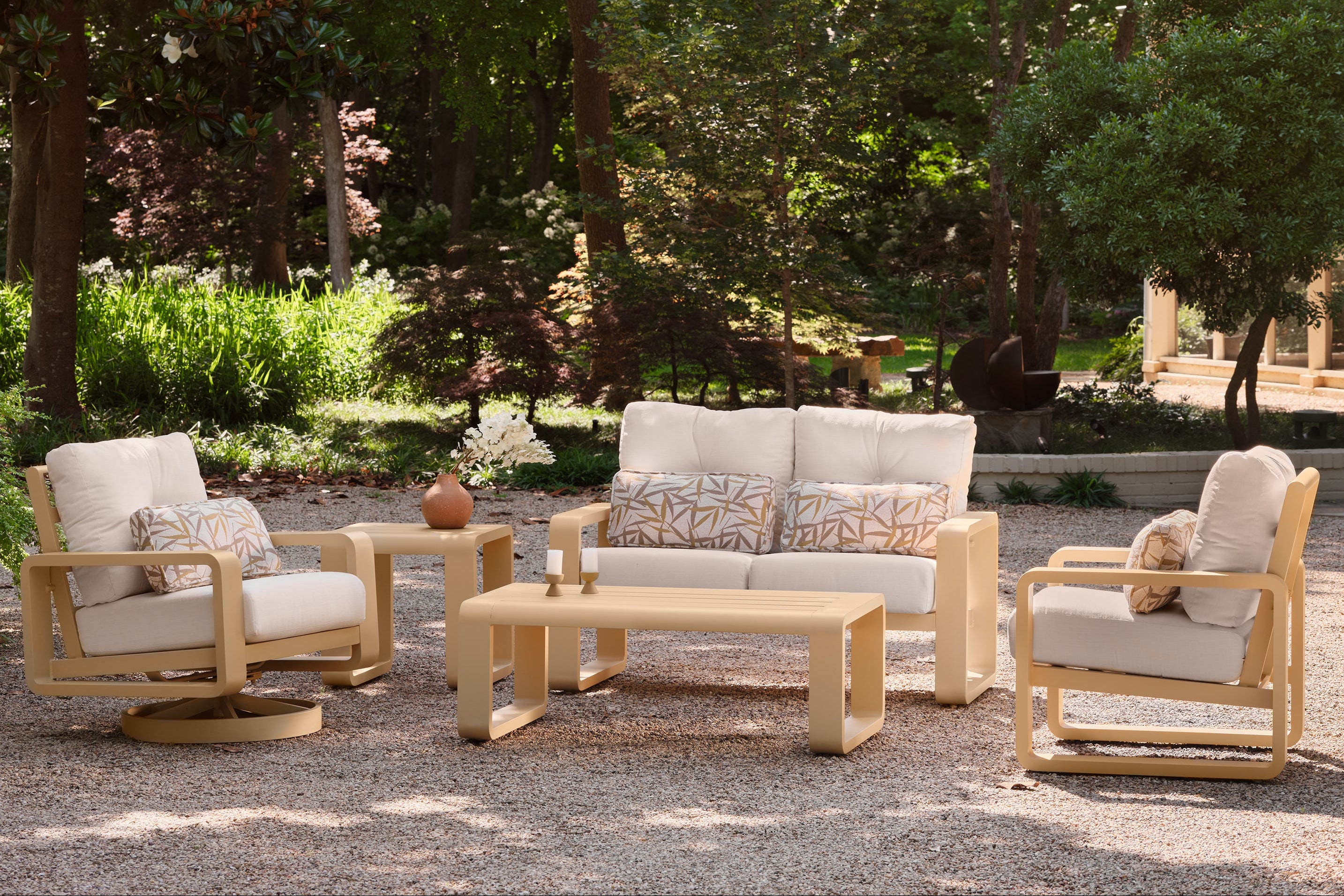 Outdoor furniture set with chairs, sofa, and coffee table in a garden setting.