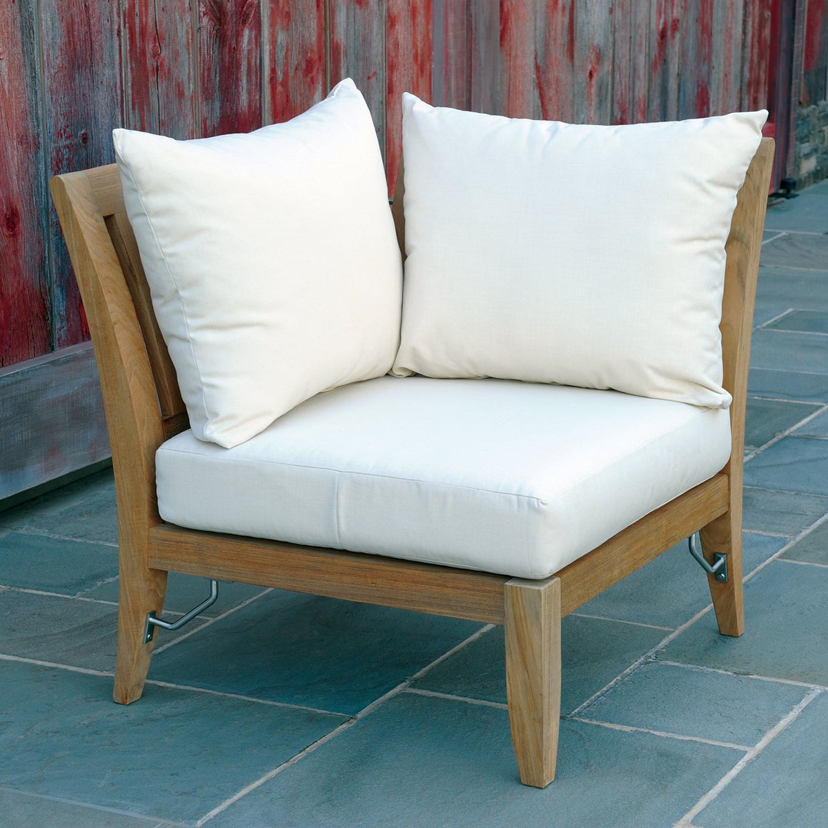 Kingsley Bate Ipanema teak sectional corner chair on a patio by a wood fence