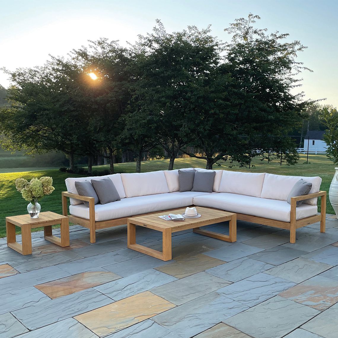 Kingsley Bate Montauk teak sectional with coffee and side tables on a stone patio