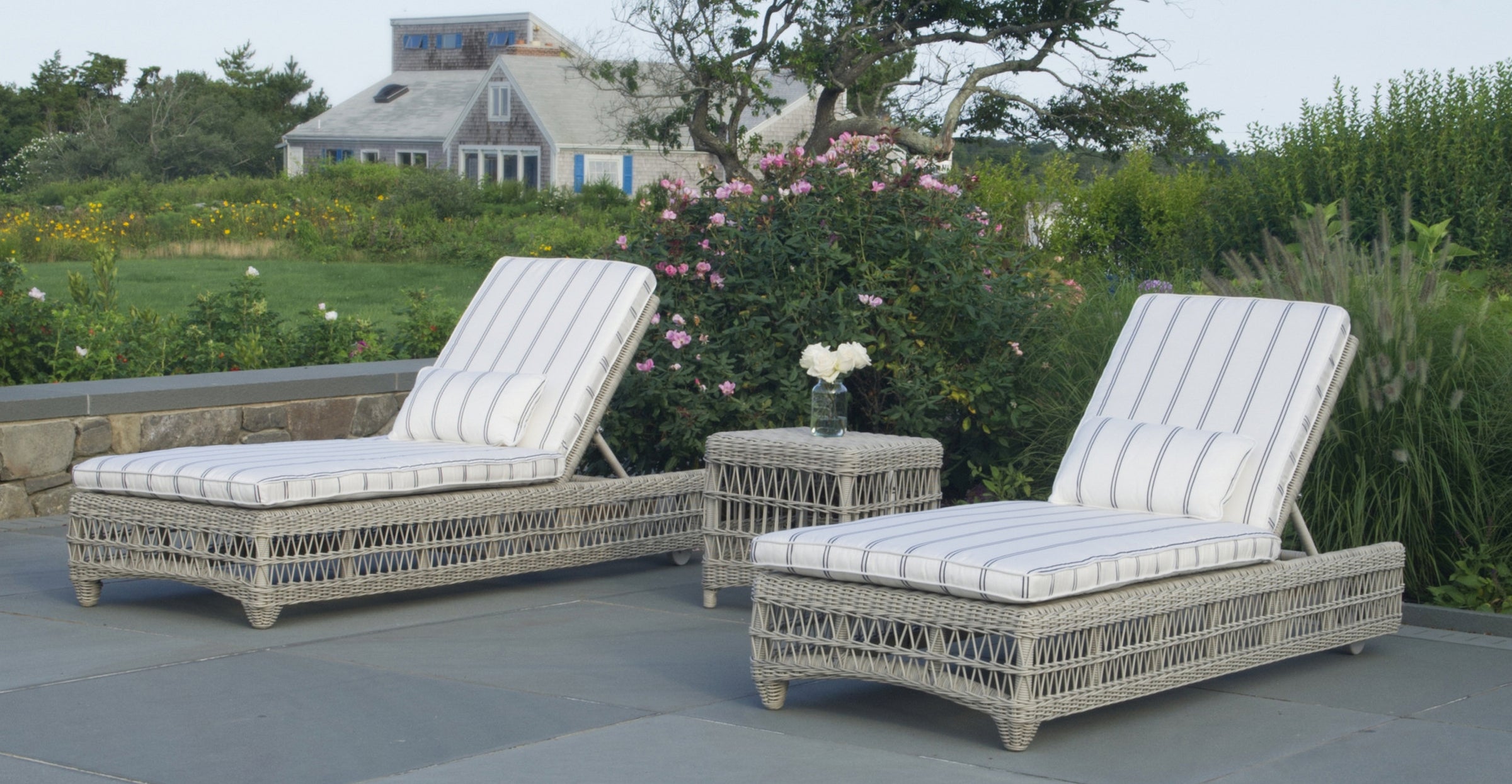 Two wicker chaise lounges with cushions on an outdoor patio